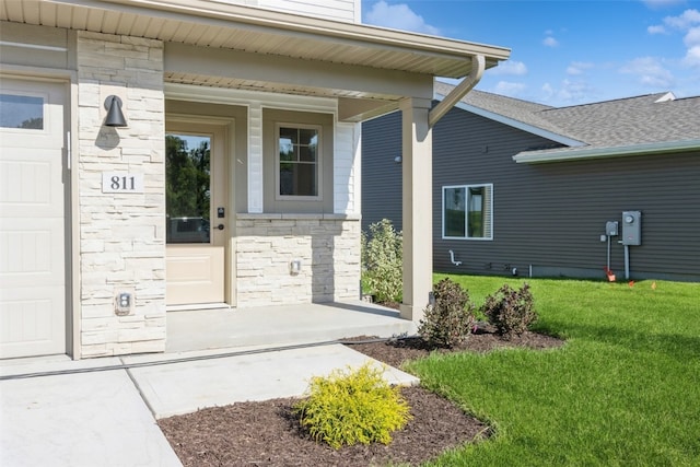 view of exterior entry with a yard and a garage