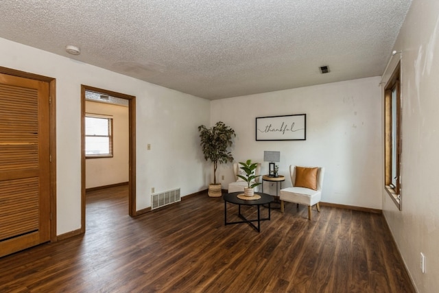 living area featuring a textured ceiling and dark hardwood / wood-style flooring