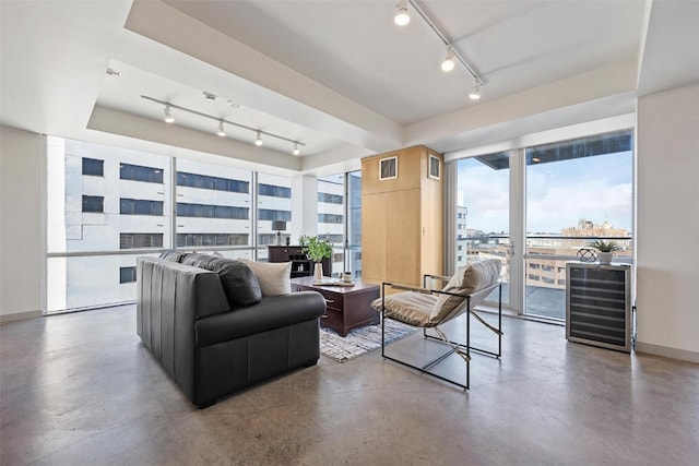 living room featuring track lighting, concrete flooring, a wall of windows, and wine cooler