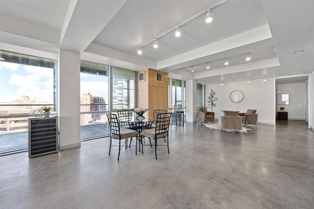 dining room with a tray ceiling, plenty of natural light, and concrete floors