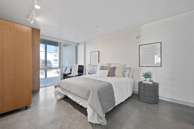 bedroom with track lighting, access to outside, and concrete floors