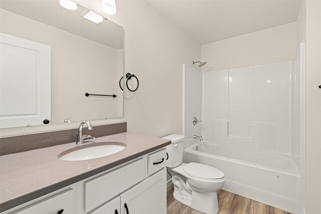 full bathroom with washtub / shower combination, hardwood / wood-style floors, toilet, and vanity