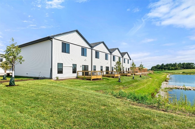 rear view of property featuring a lawn and a deck with water view