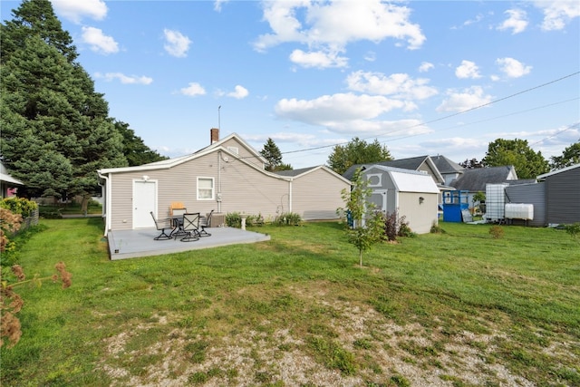 rear view of property with a lawn, a shed, and a patio area