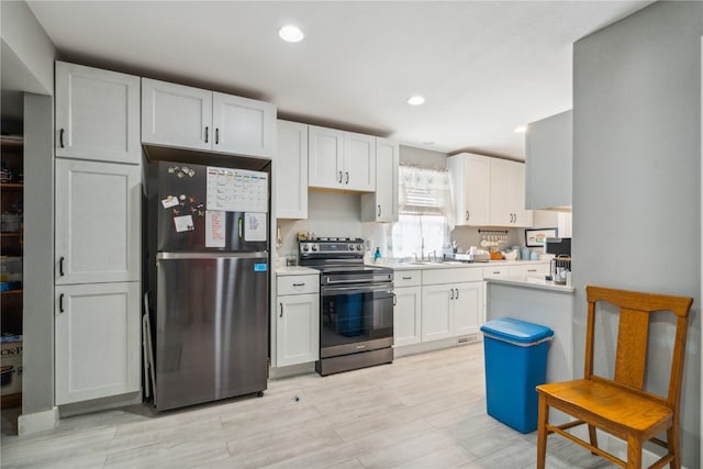 kitchen with appliances with stainless steel finishes, white cabinetry, and light hardwood / wood-style floors