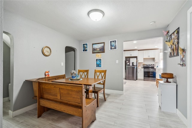 dining space with a textured ceiling and light hardwood / wood-style flooring