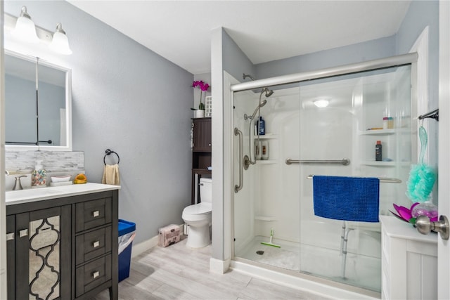 bathroom featuring vanity, toilet, wood-type flooring, and an enclosed shower