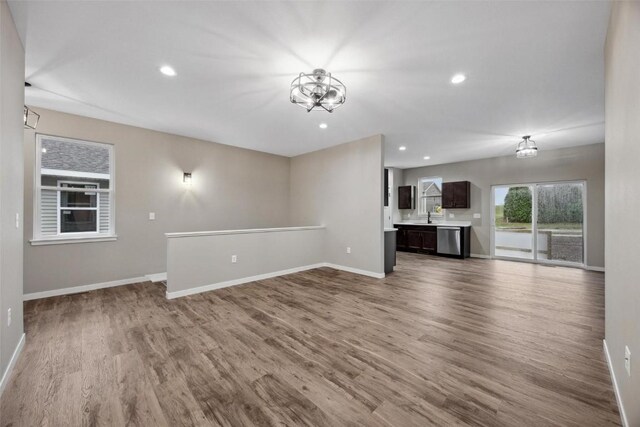 unfurnished living room with hardwood / wood-style floors, sink, and a notable chandelier