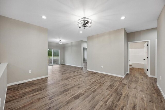 unfurnished living room with hardwood / wood-style flooring and a notable chandelier