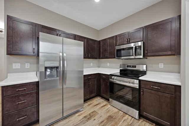 kitchen featuring stainless steel appliances, dark brown cabinets, and light hardwood / wood-style flooring