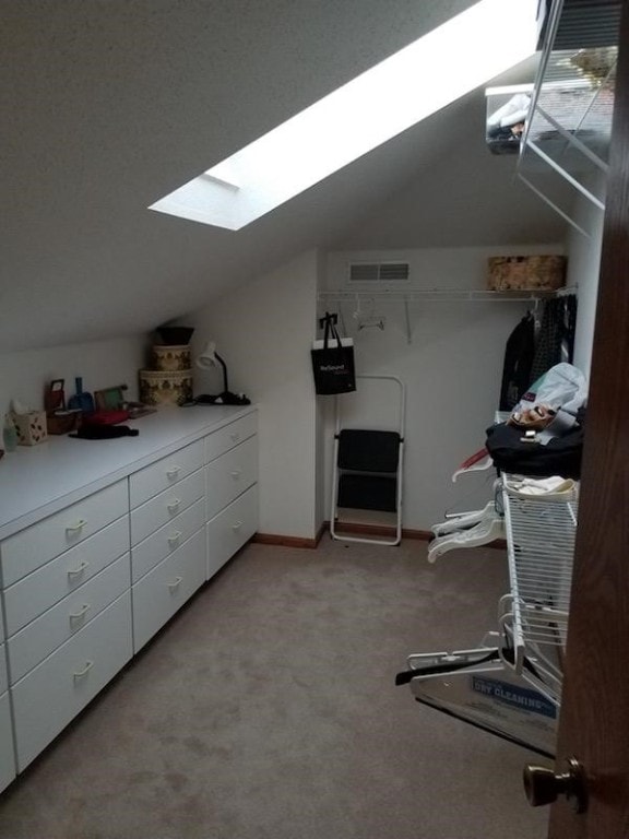 interior space featuring vaulted ceiling with skylight and light colored carpet