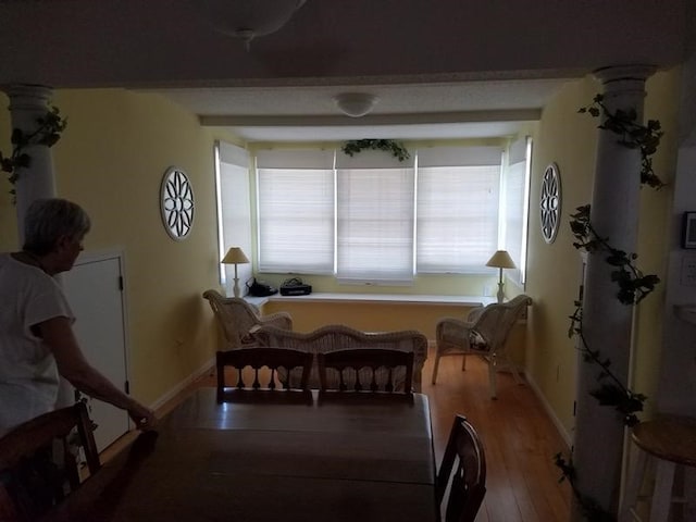 dining space with hardwood / wood-style floors, ornate columns, and beam ceiling