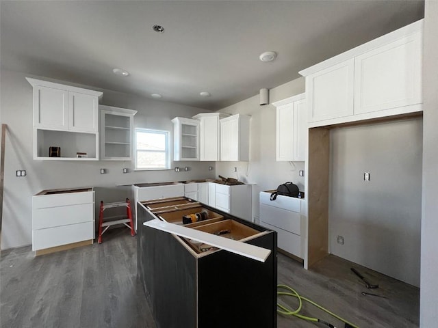 kitchen with white cabinetry, a center island, and wood-type flooring