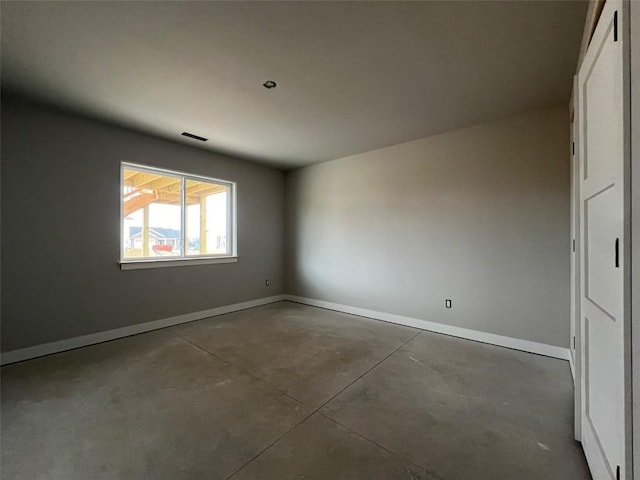 unfurnished room featuring concrete flooring, visible vents, and baseboards