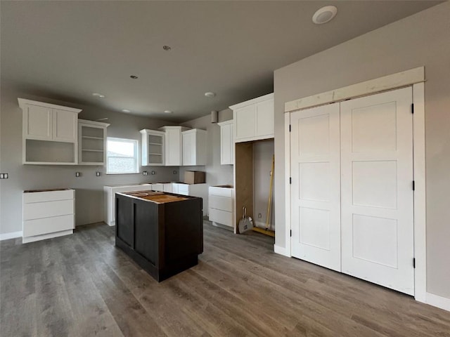 kitchen with baseboards, dark wood-type flooring, white cabinets, and a center island