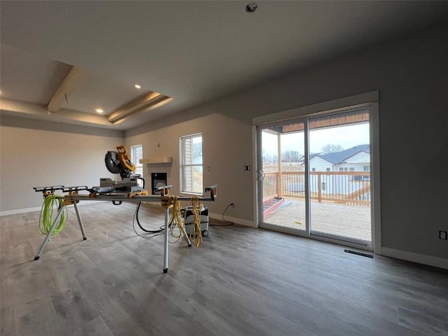 interior space featuring baseboards, visible vents, wood finished floors, and a glass covered fireplace