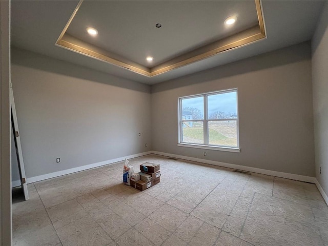 unfurnished room featuring baseboards, a raised ceiling, and recessed lighting