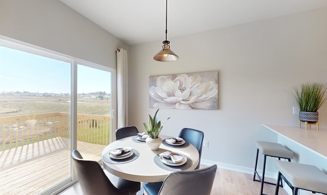 dining room featuring vaulted ceiling and light hardwood / wood-style floors