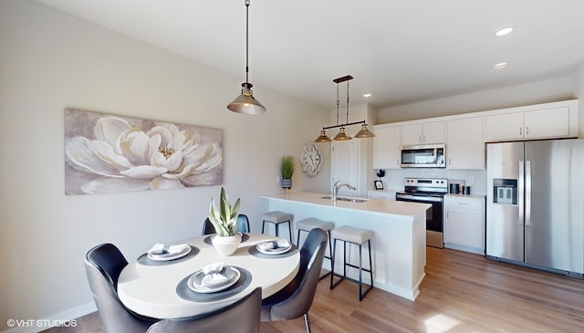 interior space with appliances with stainless steel finishes, white cabinetry, hardwood / wood-style flooring, and sink