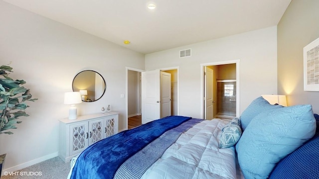 carpeted bedroom with ensuite bath, baseboards, and visible vents