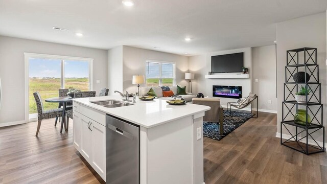 kitchen featuring sink, wood-type flooring, an island with sink, white cabinets, and stainless steel dishwasher