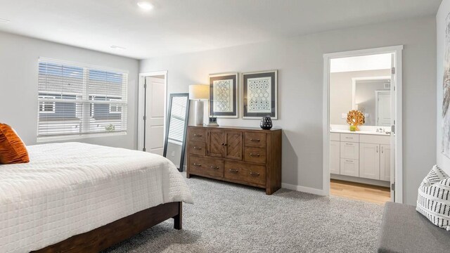 bedroom with ensuite bathroom and light carpet