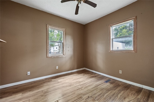 unfurnished room with light hardwood / wood-style flooring, ceiling fan, a healthy amount of sunlight, and a textured ceiling