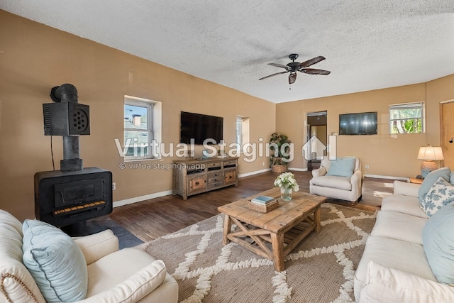 living room with a wood stove, ceiling fan, dark hardwood / wood-style floors, and a textured ceiling