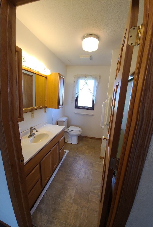 bathroom featuring a textured ceiling, vanity, and toilet