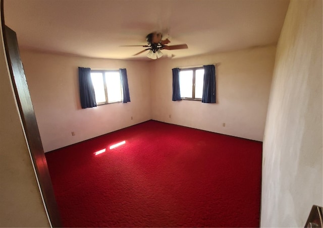 carpeted spare room with ceiling fan and plenty of natural light