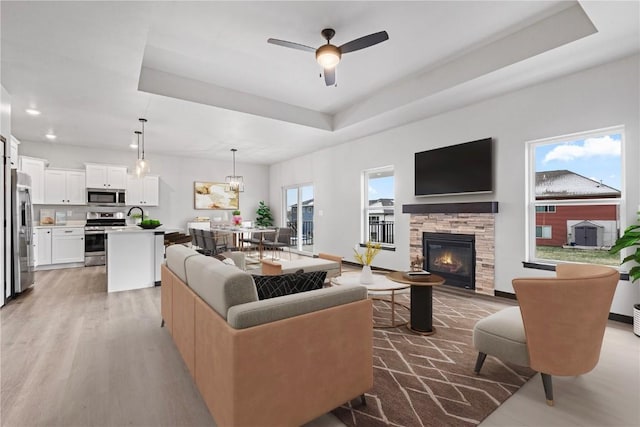 living room featuring ceiling fan, a fireplace, a healthy amount of sunlight, and hardwood / wood-style flooring