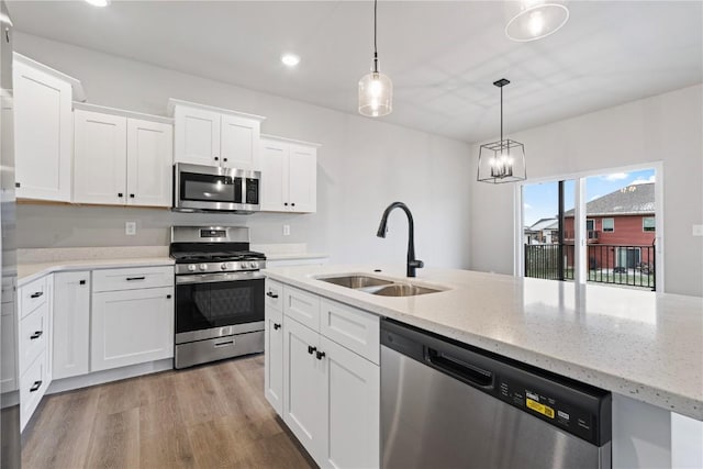 kitchen with white cabinets, appliances with stainless steel finishes, pendant lighting, and sink