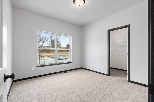 unfurnished bedroom with light carpet, a walk in closet, and a closet