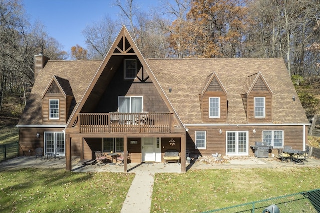 a-frame home featuring a wooden deck, a front yard, roof with shingles, and a patio