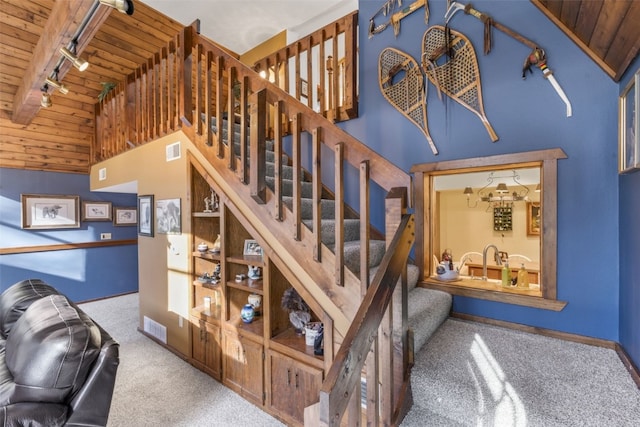 stairs featuring carpet flooring, wood ceiling, rail lighting, and high vaulted ceiling