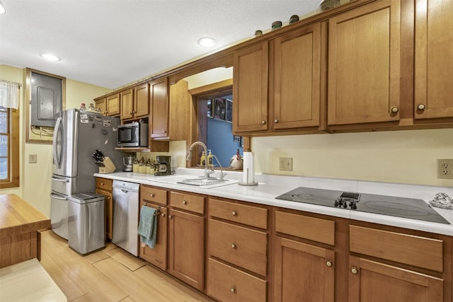 kitchen with a textured ceiling, stainless steel appliances, light hardwood / wood-style flooring, and sink