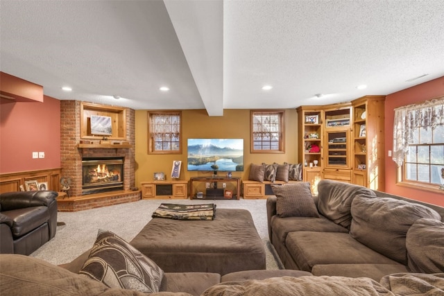 living room with carpet, a textured ceiling, a wealth of natural light, and a brick fireplace