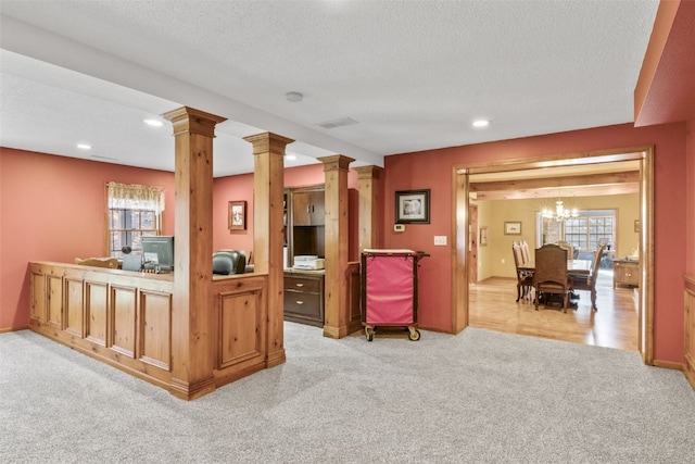 interior space with ornate columns, light colored carpet, a textured ceiling, and an inviting chandelier