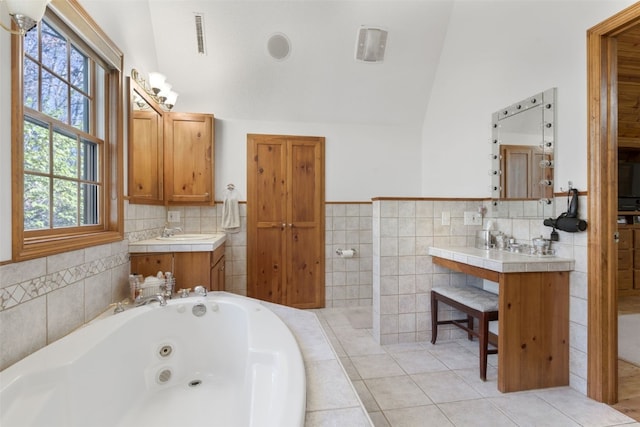 bathroom featuring tile patterned flooring, vanity, tiled tub, and vaulted ceiling