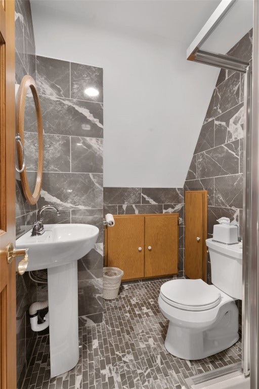 bathroom with walk in shower, vaulted ceiling, toilet, and tile walls