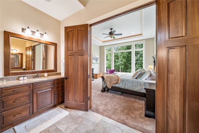 bathroom with ceiling fan, vanity, and a raised ceiling