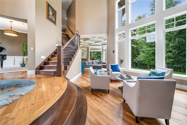 living room with a towering ceiling, light wood-type flooring, and plenty of natural light