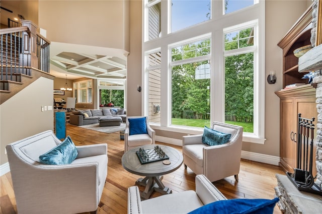 living room with light hardwood / wood-style flooring, coffered ceiling, and plenty of natural light