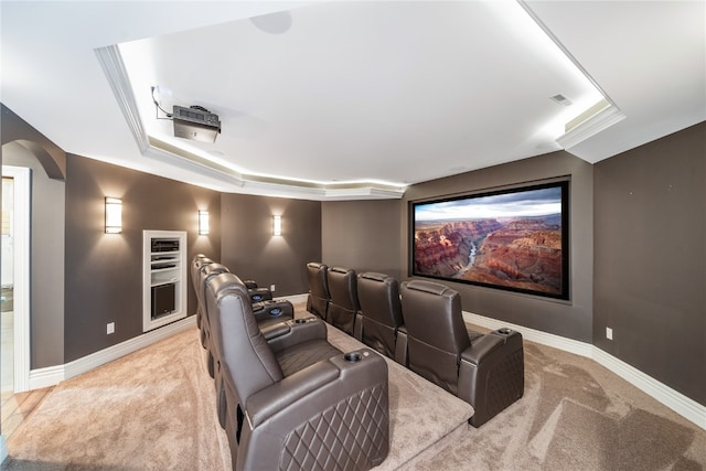 home theater room featuring crown molding, light colored carpet, and a raised ceiling