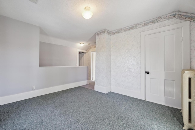 carpeted spare room featuring a textured ceiling and radiator heating unit