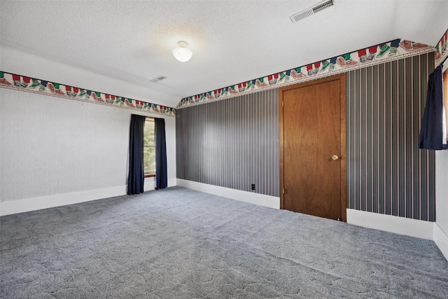 empty room with a textured ceiling, carpet flooring, and vaulted ceiling