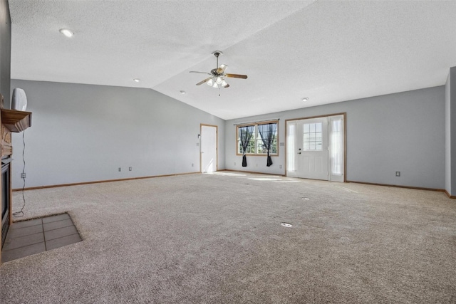 unfurnished living room featuring ceiling fan, a textured ceiling, light colored carpet, a fireplace, and vaulted ceiling