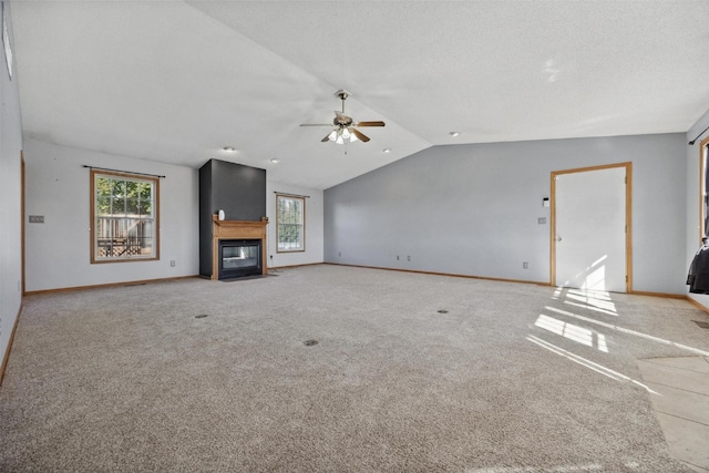 unfurnished living room with lofted ceiling, ceiling fan, carpet flooring, and a textured ceiling