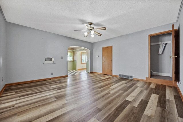 unfurnished bedroom with a textured ceiling, wood-type flooring, and ceiling fan