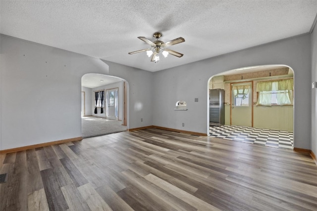 unfurnished room with wood-type flooring, ceiling fan, a healthy amount of sunlight, and a textured ceiling